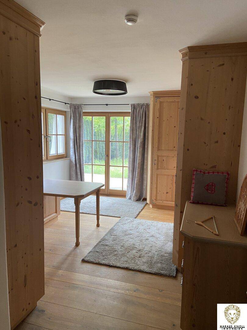 Vielseitiger Raum mit Holzboden, Einbauschränken und Zugang zu einem Balkon.