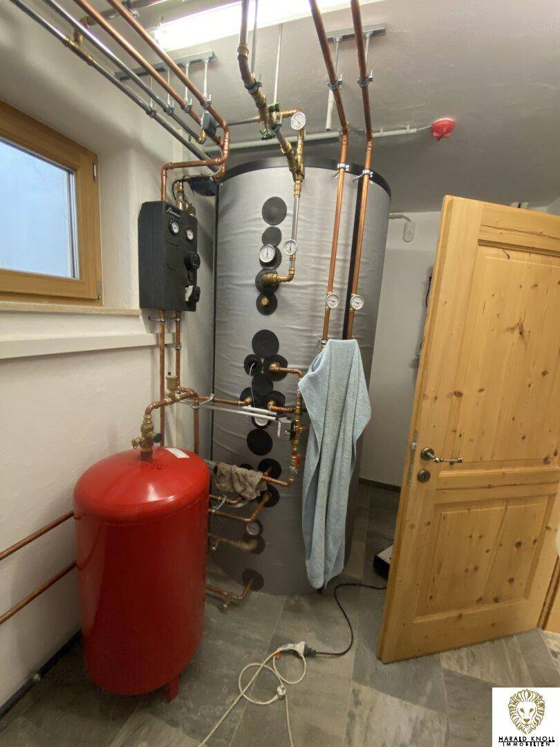 Technikraum mit Heizungsanlage und Warmwasserspeicher im Kellerbereich.