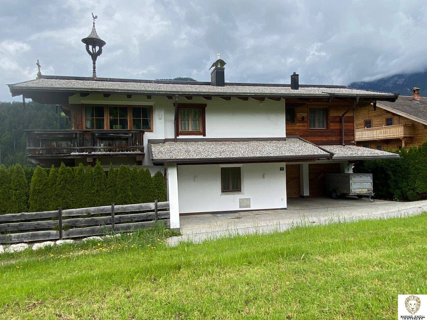 Alpenländisches Haus mit Holzfassade, weißem Putz und integriertem Carport.