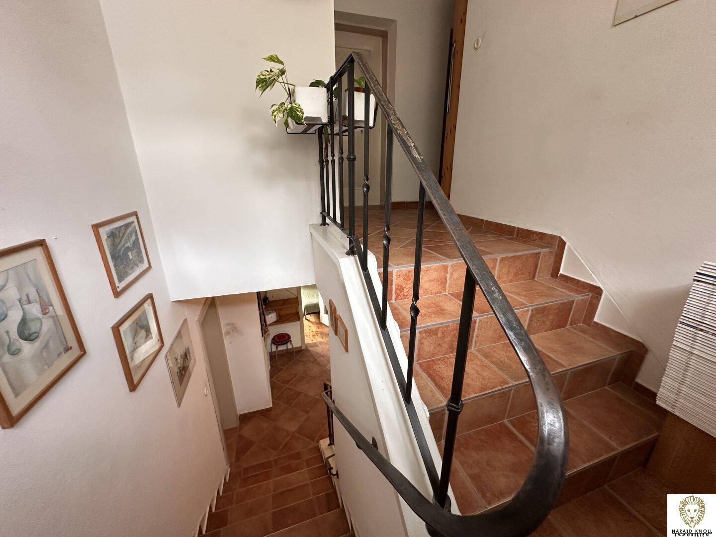 Rustikale Treppe mit gefliesten Stufen und schmiedeeisernem Geländer, verbindet die Stockwerke.