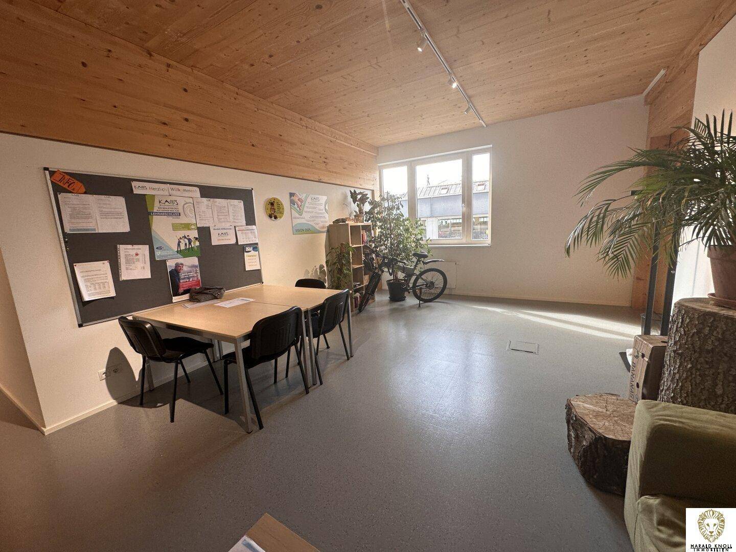 Geräumiger Bürobereich mit Holzwänden, Pinnwand und Pflanzen, bietet eine angenehme Arbeitsatmosphäre.