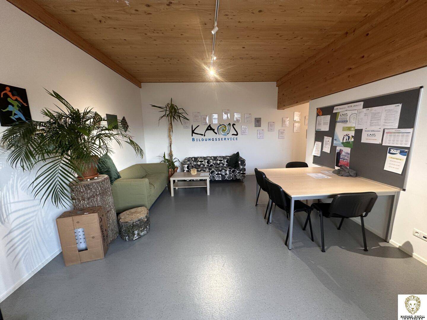 Offener Bürobereich mit Sitzgelegenheiten, Pinnwand und Pflanzen, ideal für kreatives Arbeiten.