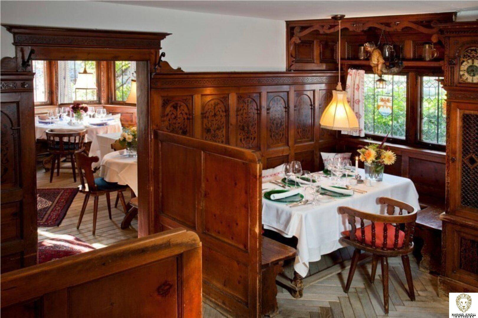 Gemütlicher Essbereich mit traditionellen Holzvertäfelungen und Blick ins Grüne durch die Fenster.