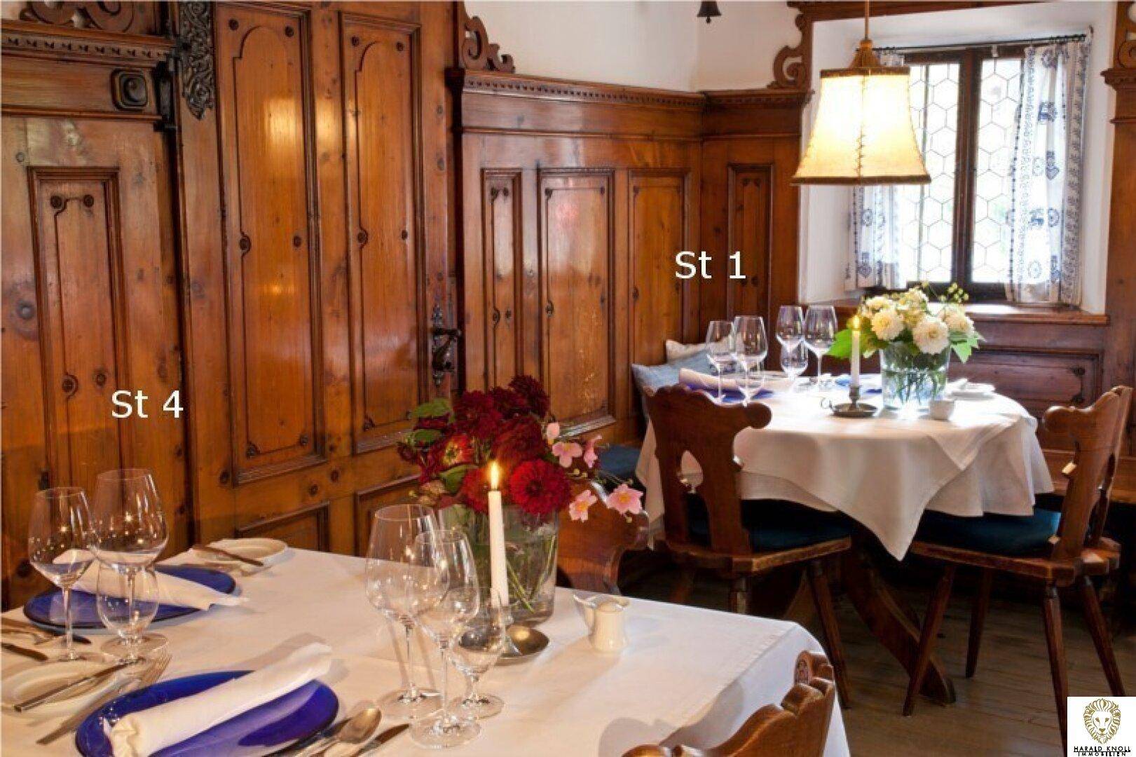 Gemütlicher Essbereich mit Holzwänden, weiß gedeckten Tischen und frischen Blumenarrangements.