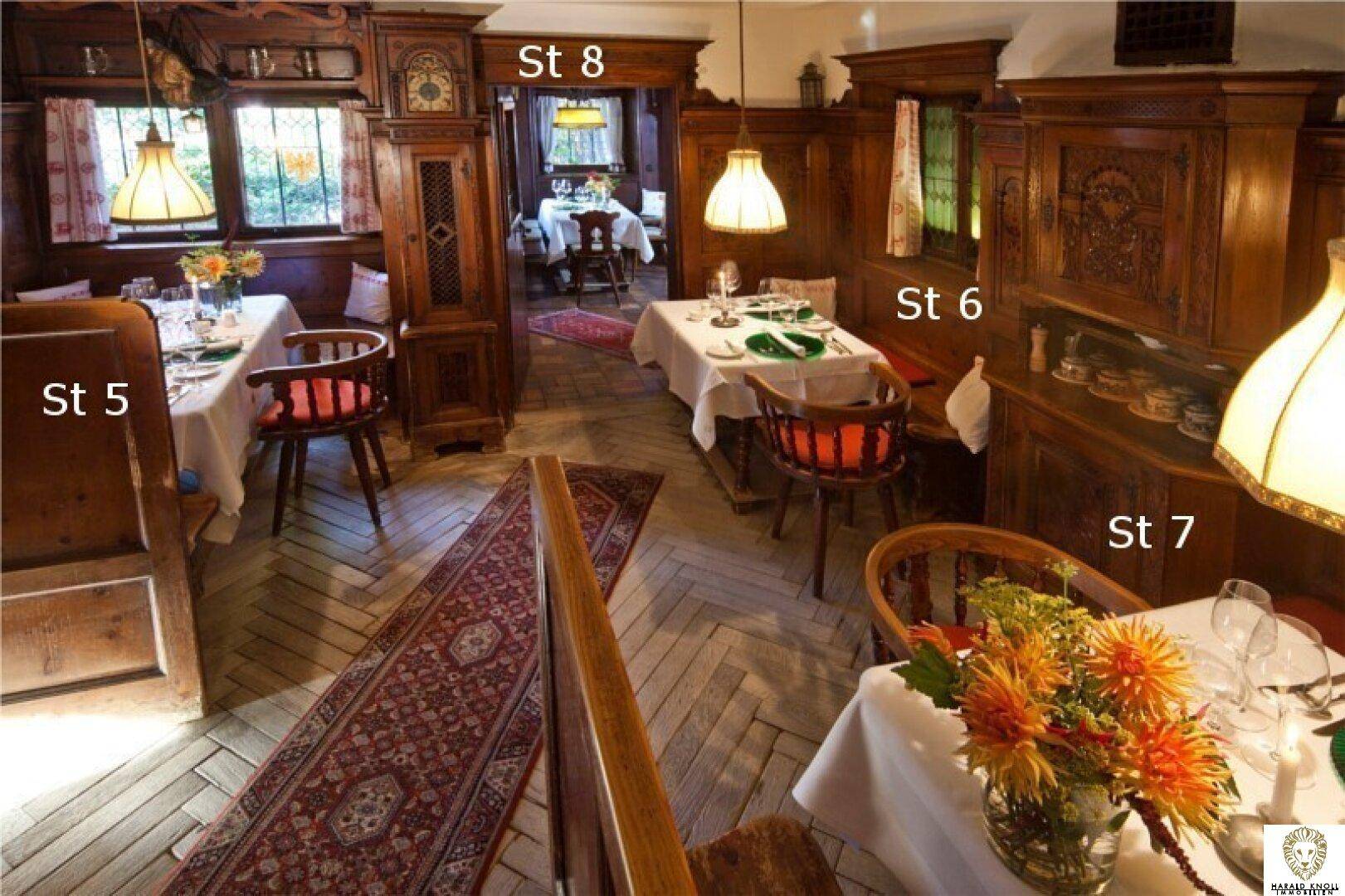 Traditioneller Gastraum mit dunklen Holzvertäfelungen, Teppichen und gedeckten Tischen.