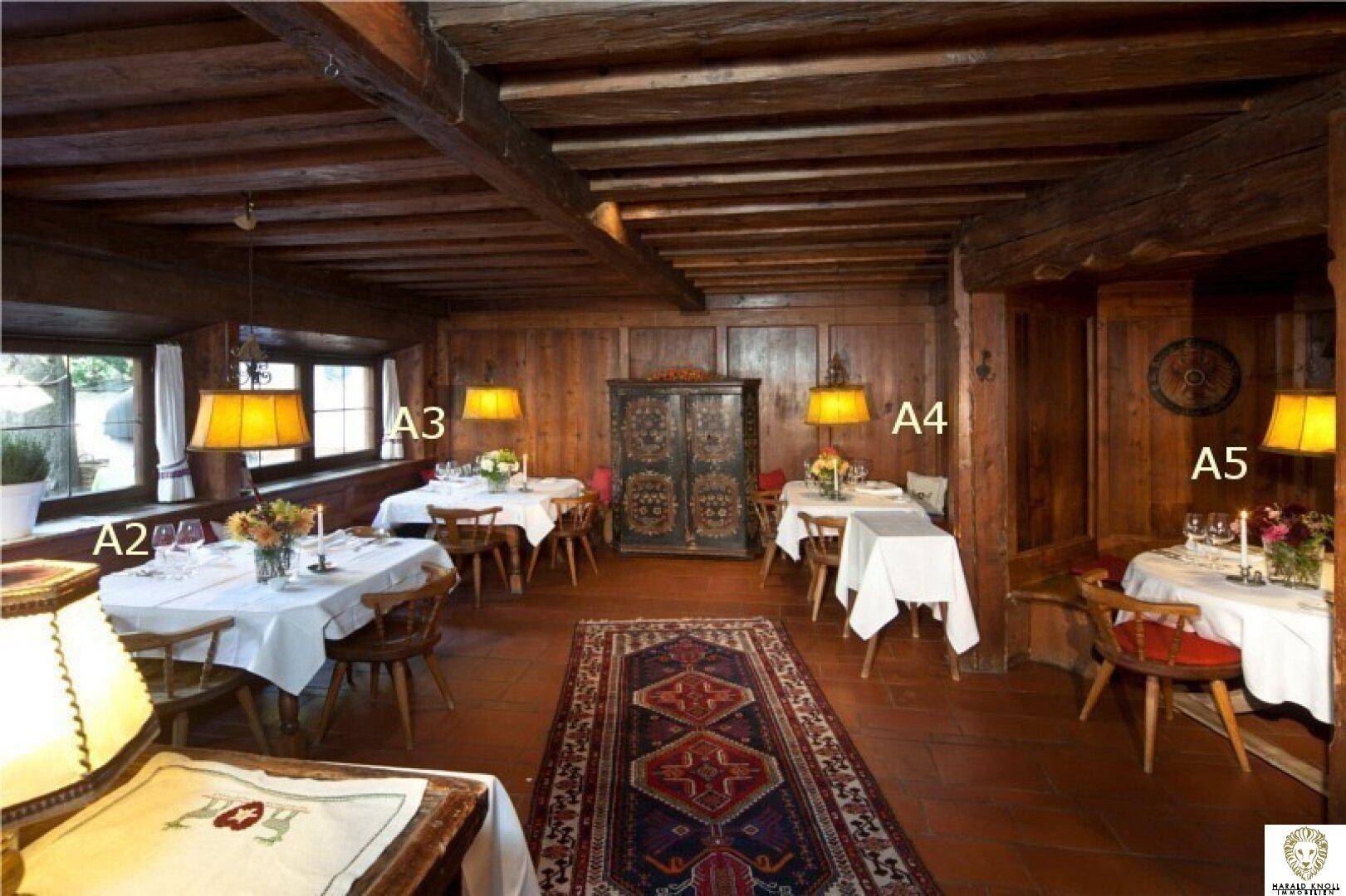 Rustikaler Gastraum mit Holzbalkendecke, Terrakottafliesen und traditionellen Möbeln.