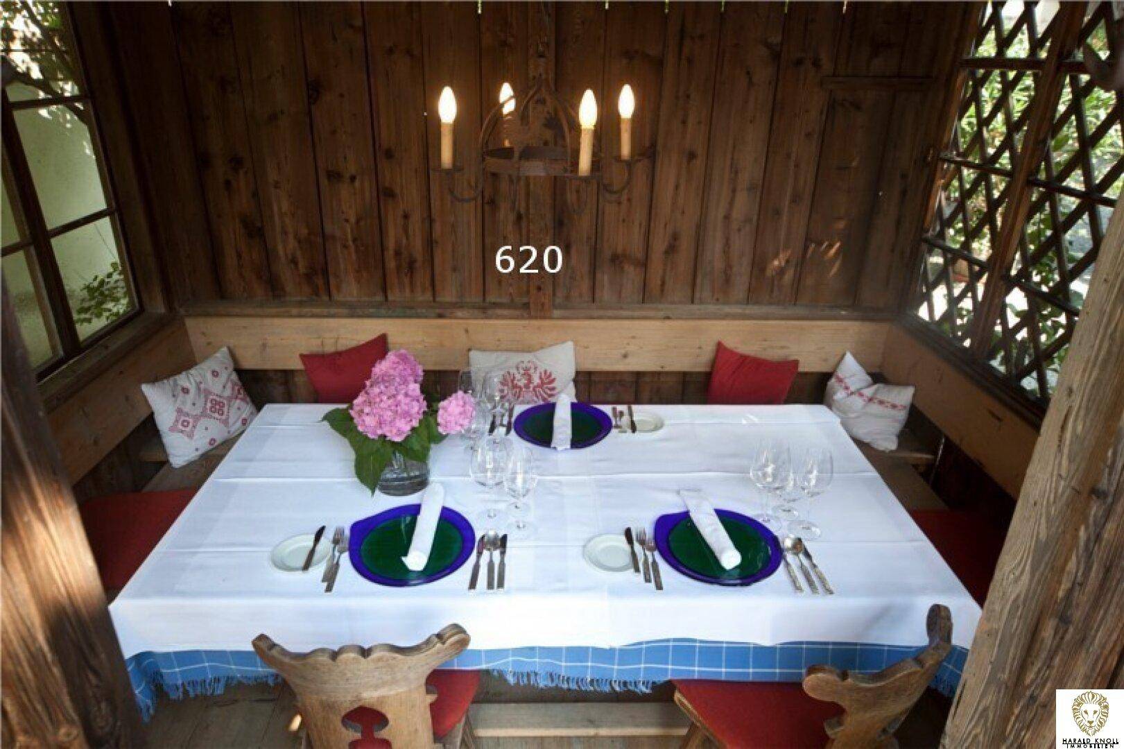 Gemütlicher Pavillon im Garten, festlich gedeckt für eine Mahlzeit im Freien.