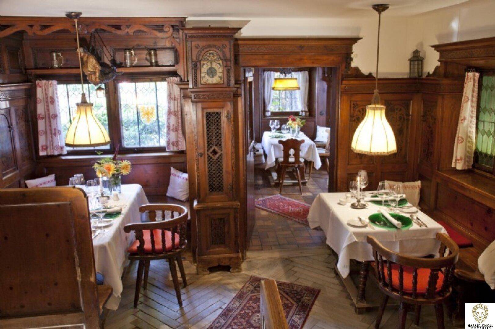 Traditioneller Speisesaal mit dunkler Holzvertäfelung, gedeckten Tischen und gemütlicher Beleuchtung.