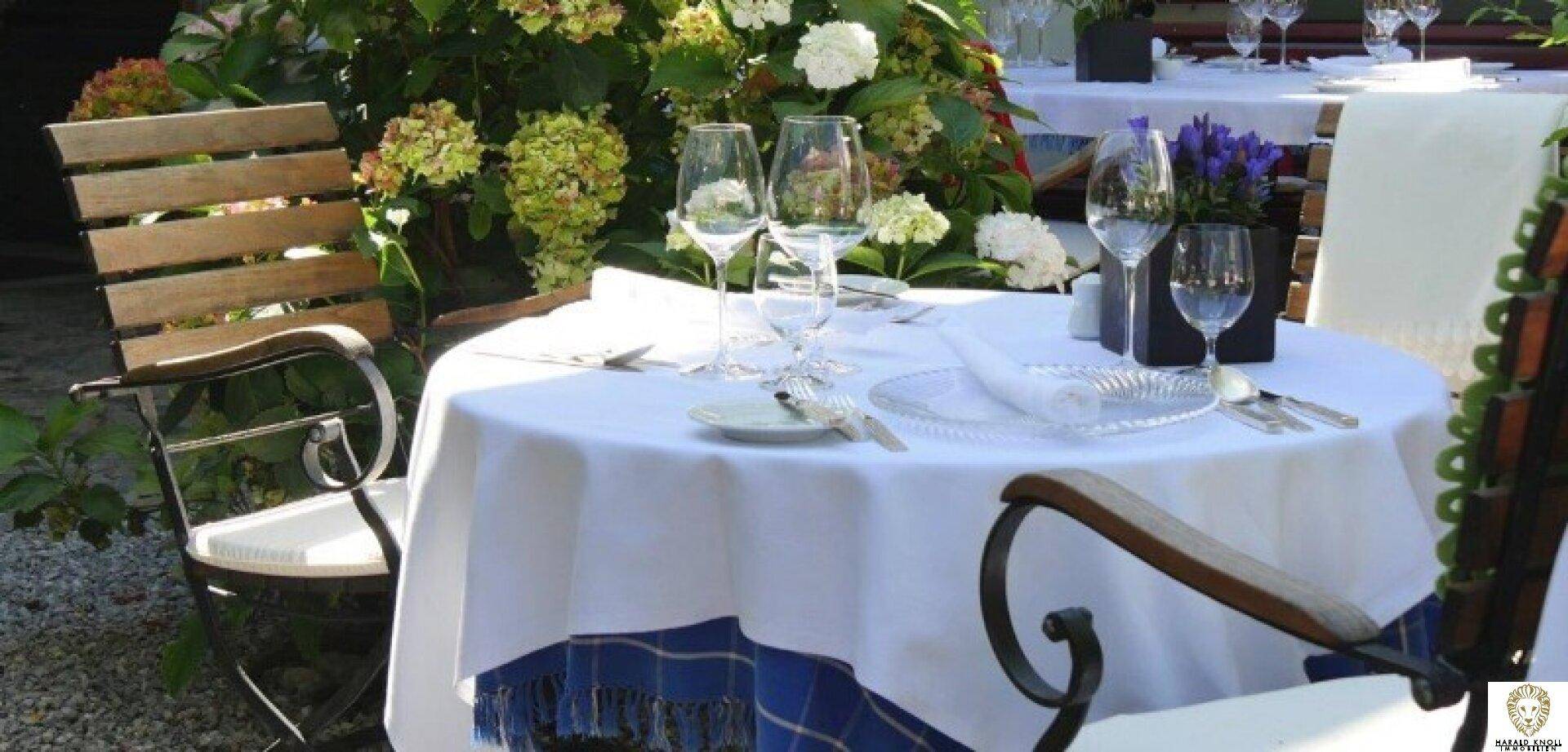 Außenbereich mit gedecktem Tisch, umgeben von üppigen Blumen und Pflanzen, ideal für Mahlzeiten im Freien.