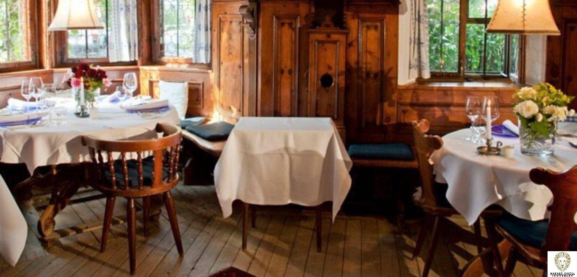 Traditioneller Speisesaal mit Holzböden und -vertäfelung, mehreren gedeckten Tischen und warmem Licht.