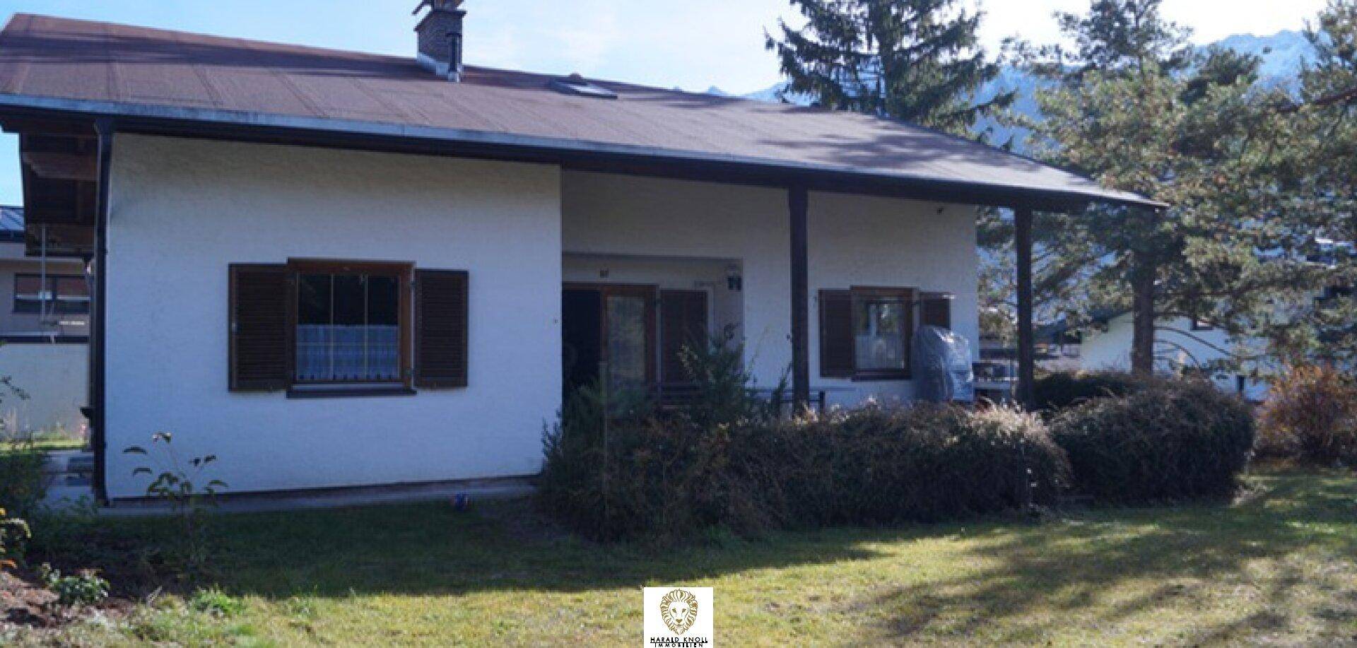 Vorderansicht des Hauses mit Gartenbereich, Rasen und traditionellen Holzfensterläden.