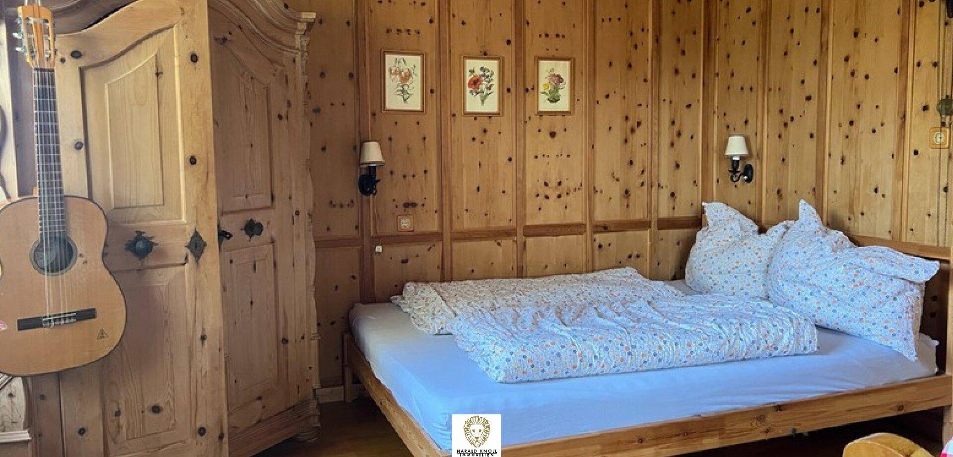 Schlafzimmer im alpinen Stil mit Holztäfelung an den Wänden und einem gemütlichen Holzbett.