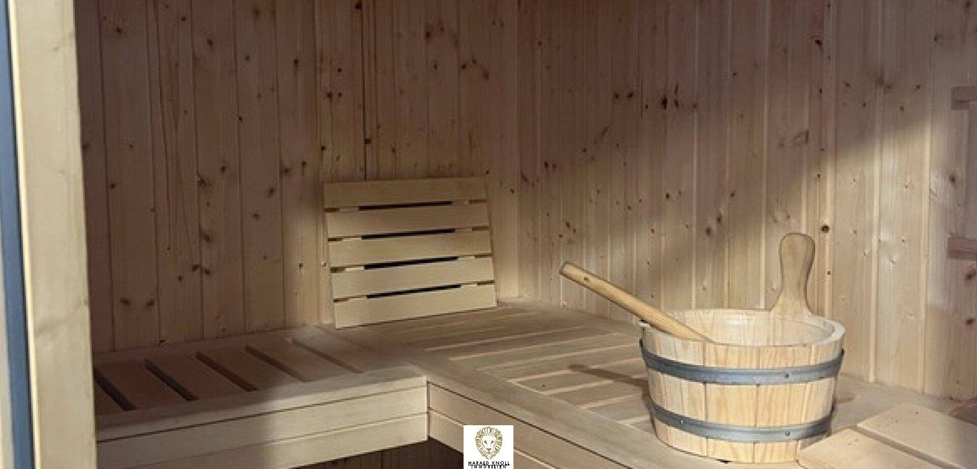Traditionelle Holzsauna mit Bänken und Saunaeimer für entspannende Wellnessmomente.