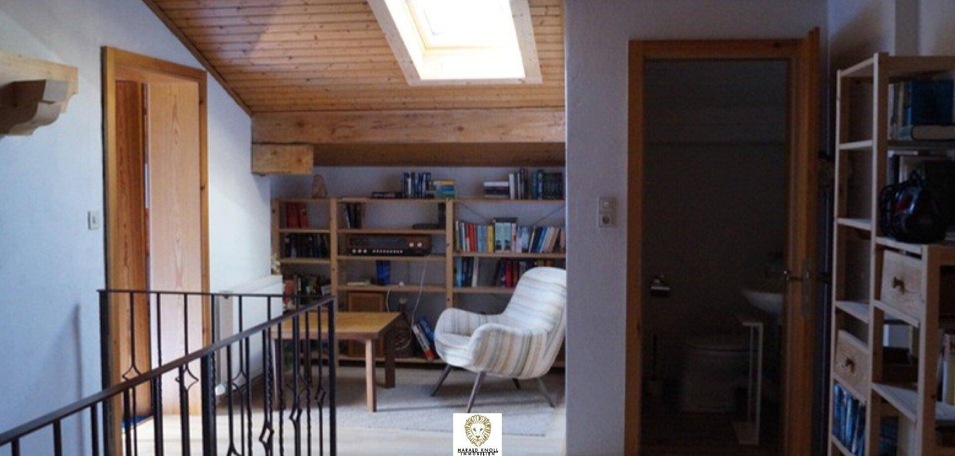 Heller Dachbodenbereich mit Holzdecke, Dachfenster und Bücherregalen, ideal als Leseecke.