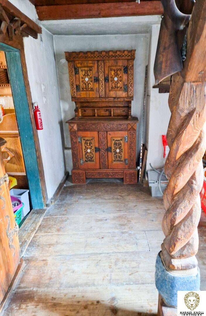 Schmaler Flur mit einem antiken Holzschrank und rustikalen Holzbalken an der Decke.