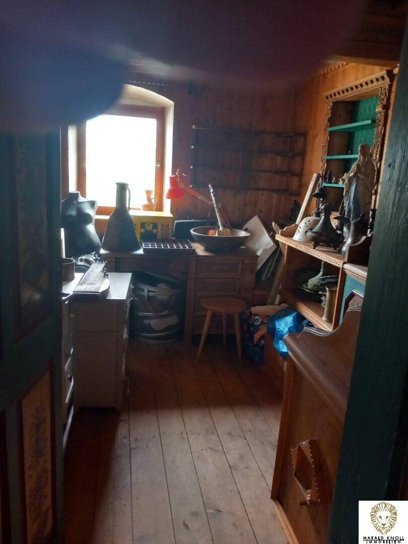 Kleines Arbeitszimmer mit Holzvertäfelung, einem Schreibtisch und verschiedenen Dekorationsgegenständen.