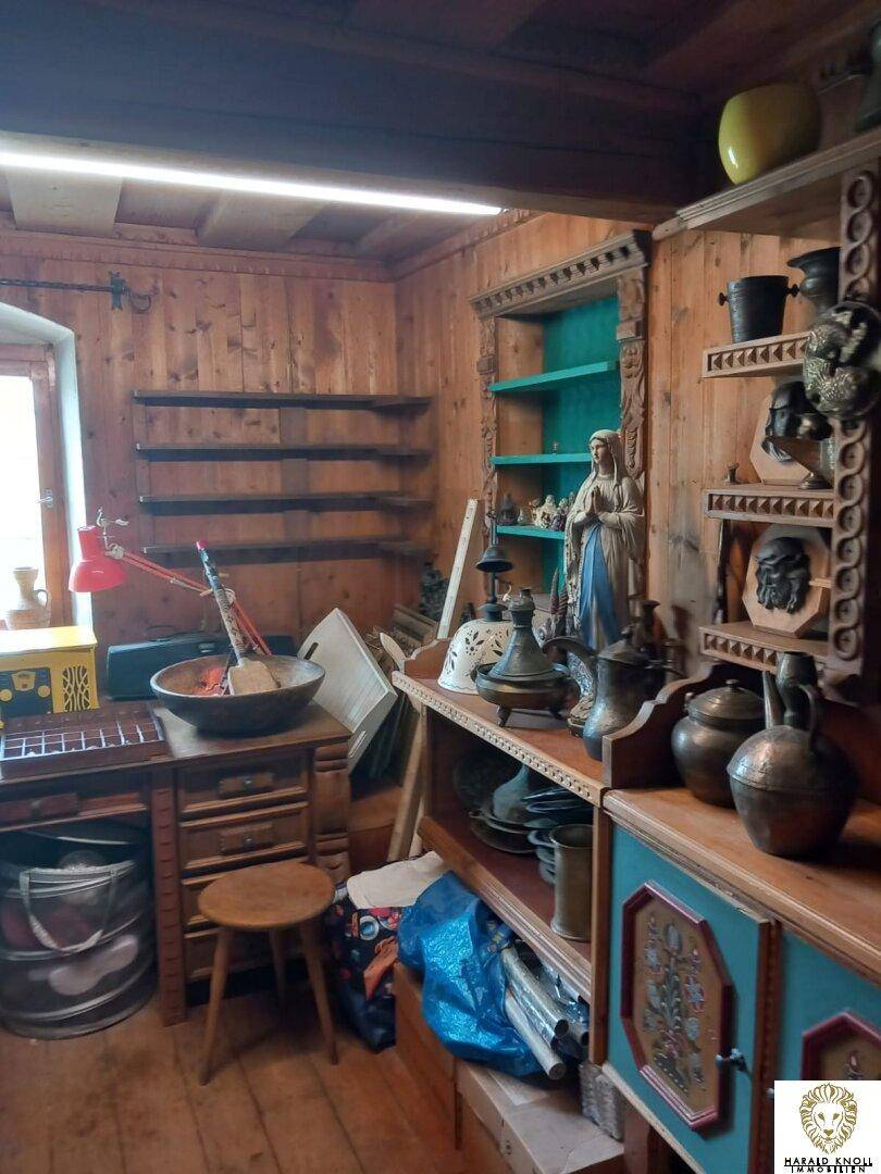 Rustikales Arbeitszimmer mit Holzvertäfelung, Regalen und einem Schreibtischbereich am Fenster.