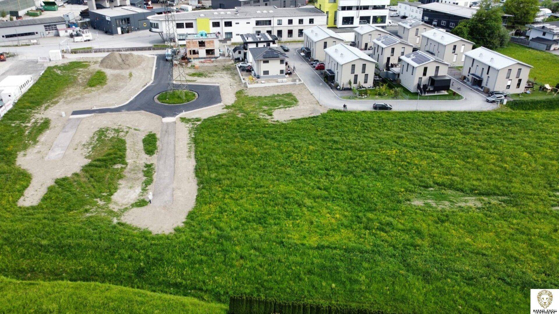 Luftaufnahme eines Baugebiets mit neuen Häusern, Straßen und viel Grünfläche im ländlichen Raum.