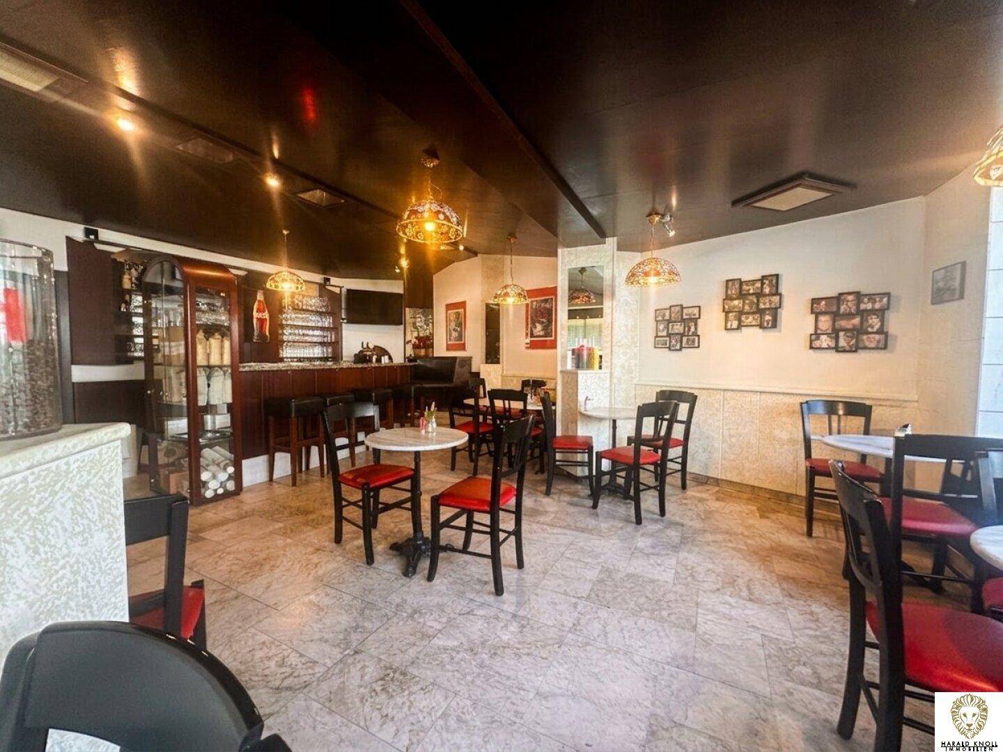 Geräumiger Café-Innenraum mit Sitzgelegenheiten, einer Bar und dekorativen Hängelampen.