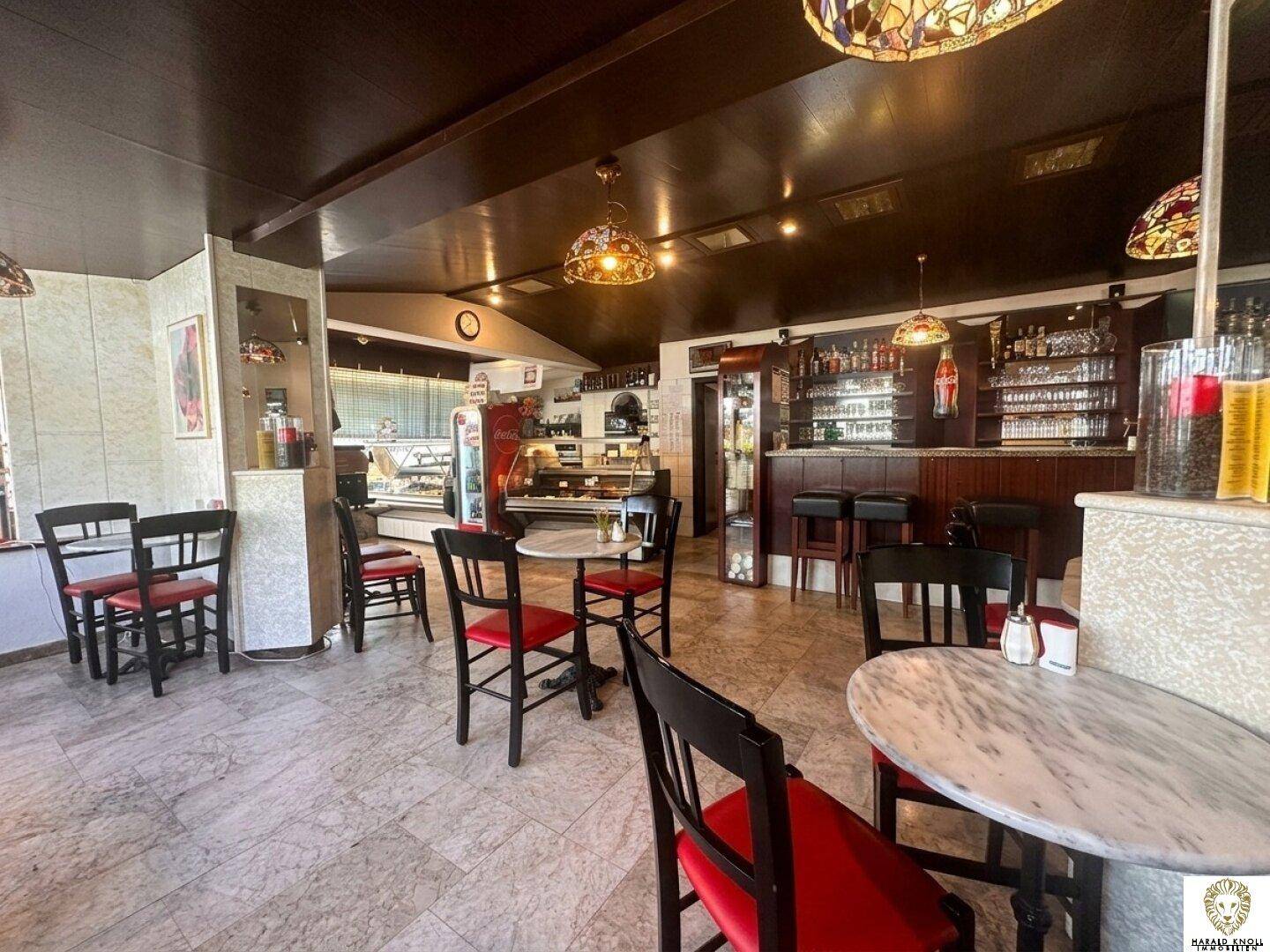 Einladender Café-Bereich mit Sitzgelegenheiten, einer gut ausgestatteten Bar und Auslagen für Gebäck.