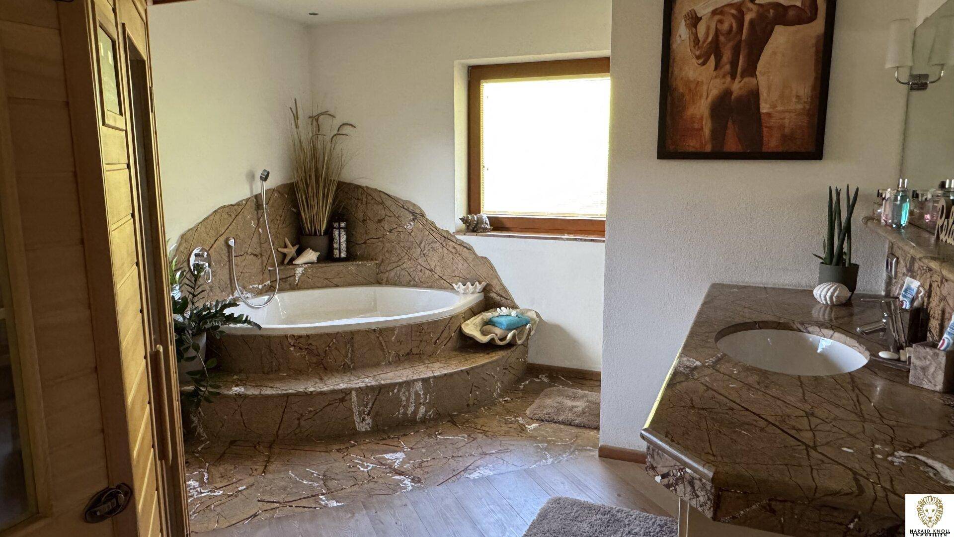 Individuell gestaltetes Badezimmer mit eingelassener Badewanne und Naturstein-Elementen.