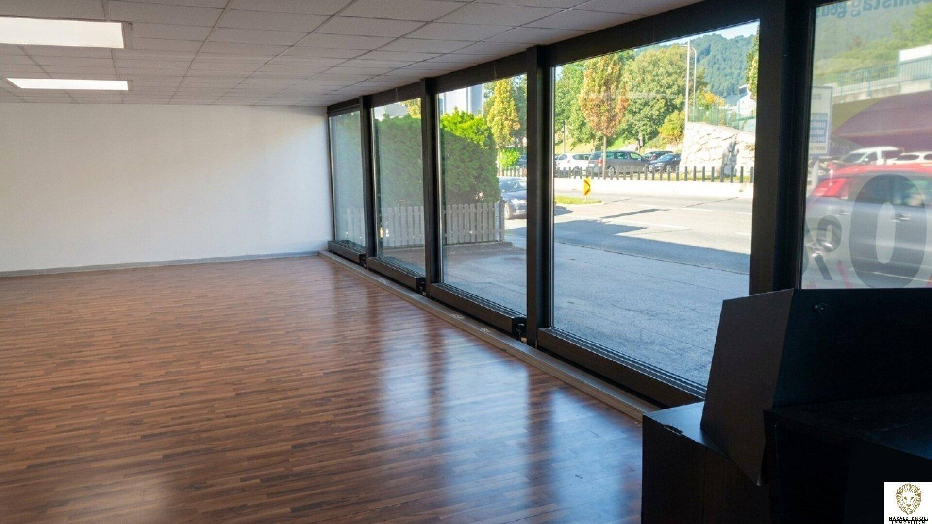 Geräumiger, leerer Geschäftsraum mit großen Fenstern, die viel Tageslicht hereinlassen und auf die Straße blicken.