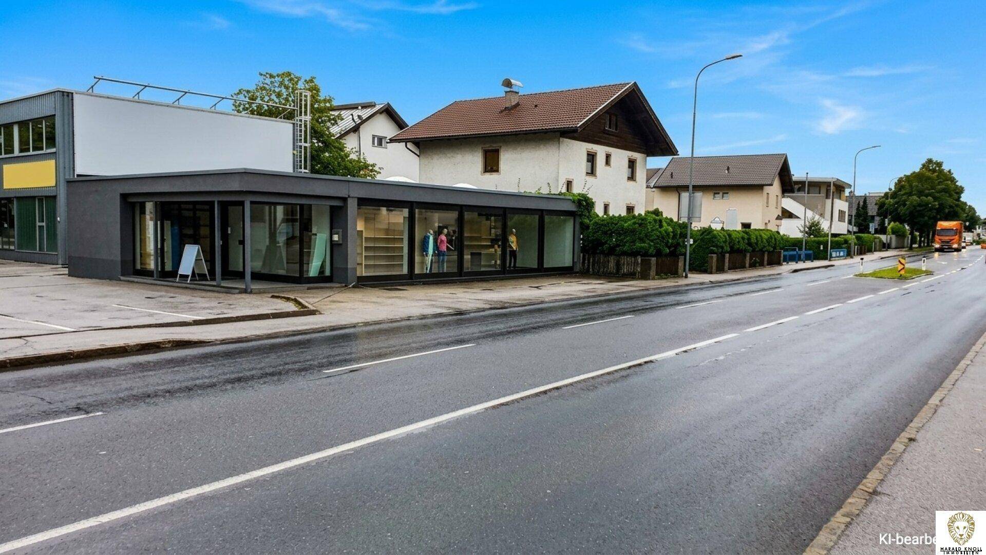 Ansicht des modernen Geschäftsgebäudes von der Straße aus, mit klarem Himmel und nasser Fahrbahn.