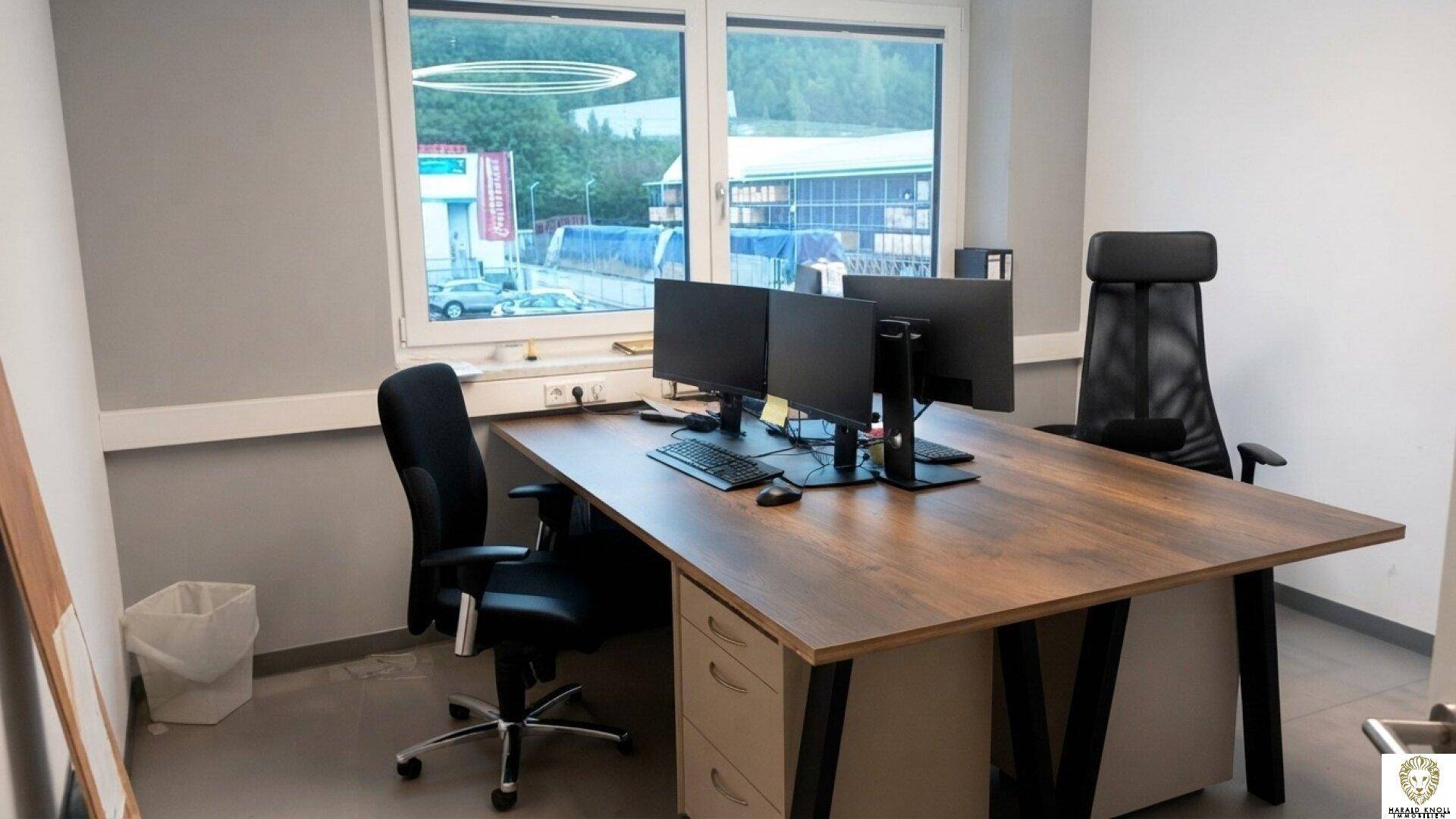 Modernes Büro mit großem Holzschreibtisch, zwei Monitoren und ergonomischen Bürostühlen.