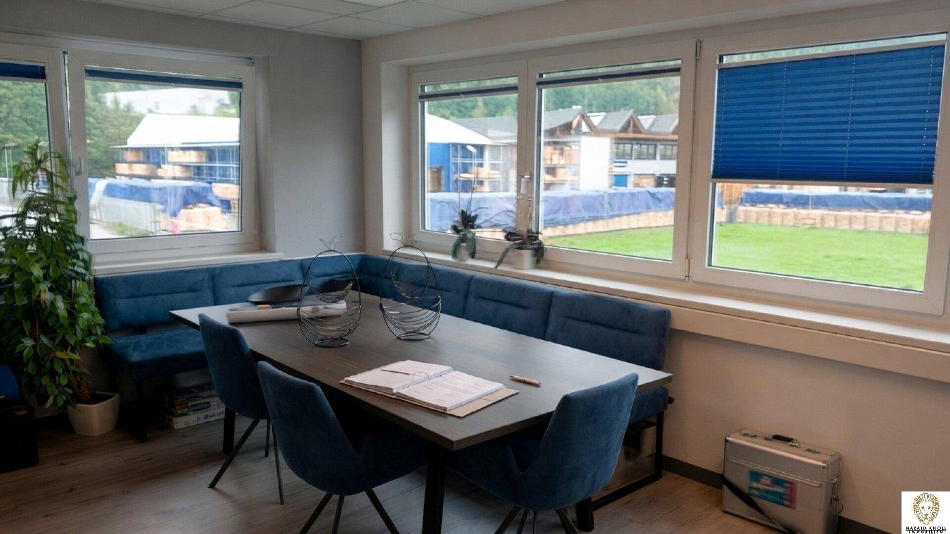 Heller Besprechungsraum mit blauen Sitzbänken, einem langen Tisch und großen Fenstern.