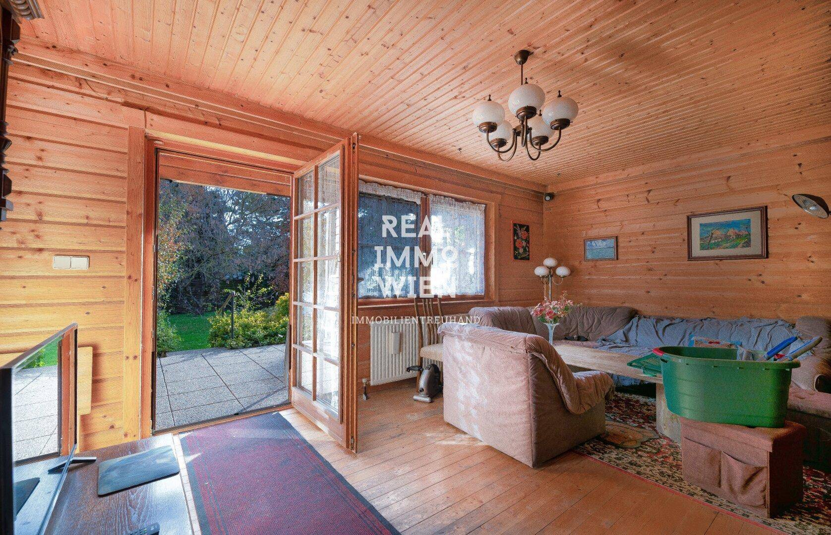 Gemütliches Wohnzimmer mit Holzwänden, Holzboden und direktem Zugang zur Terrasse.