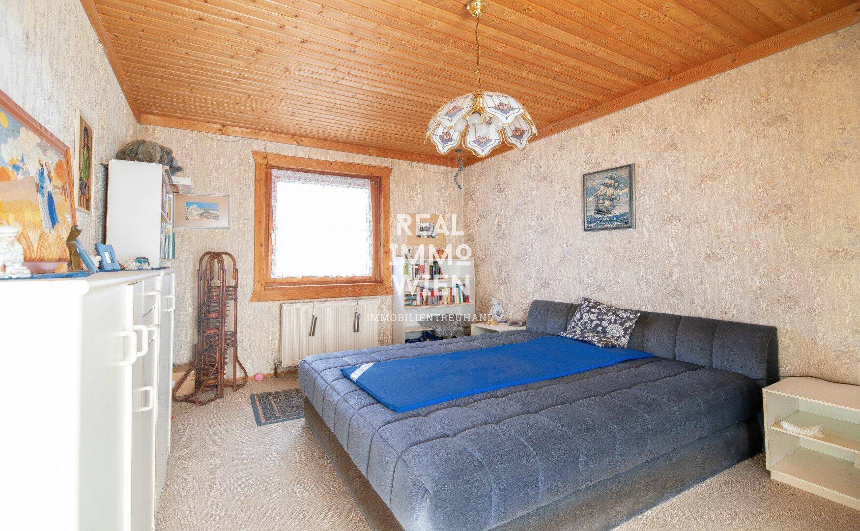 Schlafzimmer mit gemusterter Tapete, Teppichboden und einem großen Bett.