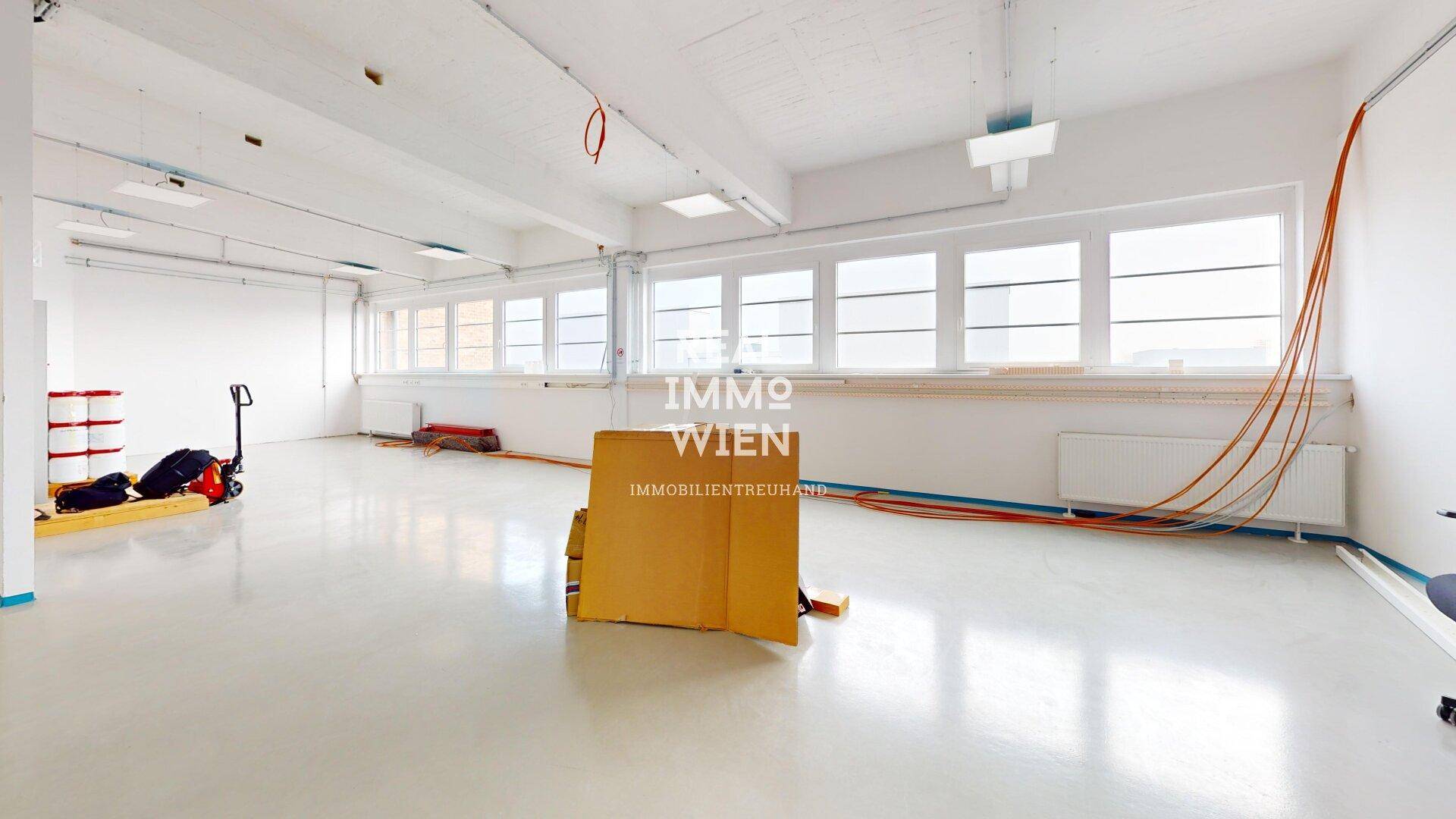 Großer, heller Büroraum mit vielen Fenstern, hohen Decken und glänzendem Boden, bereit zur Fertigstellung.