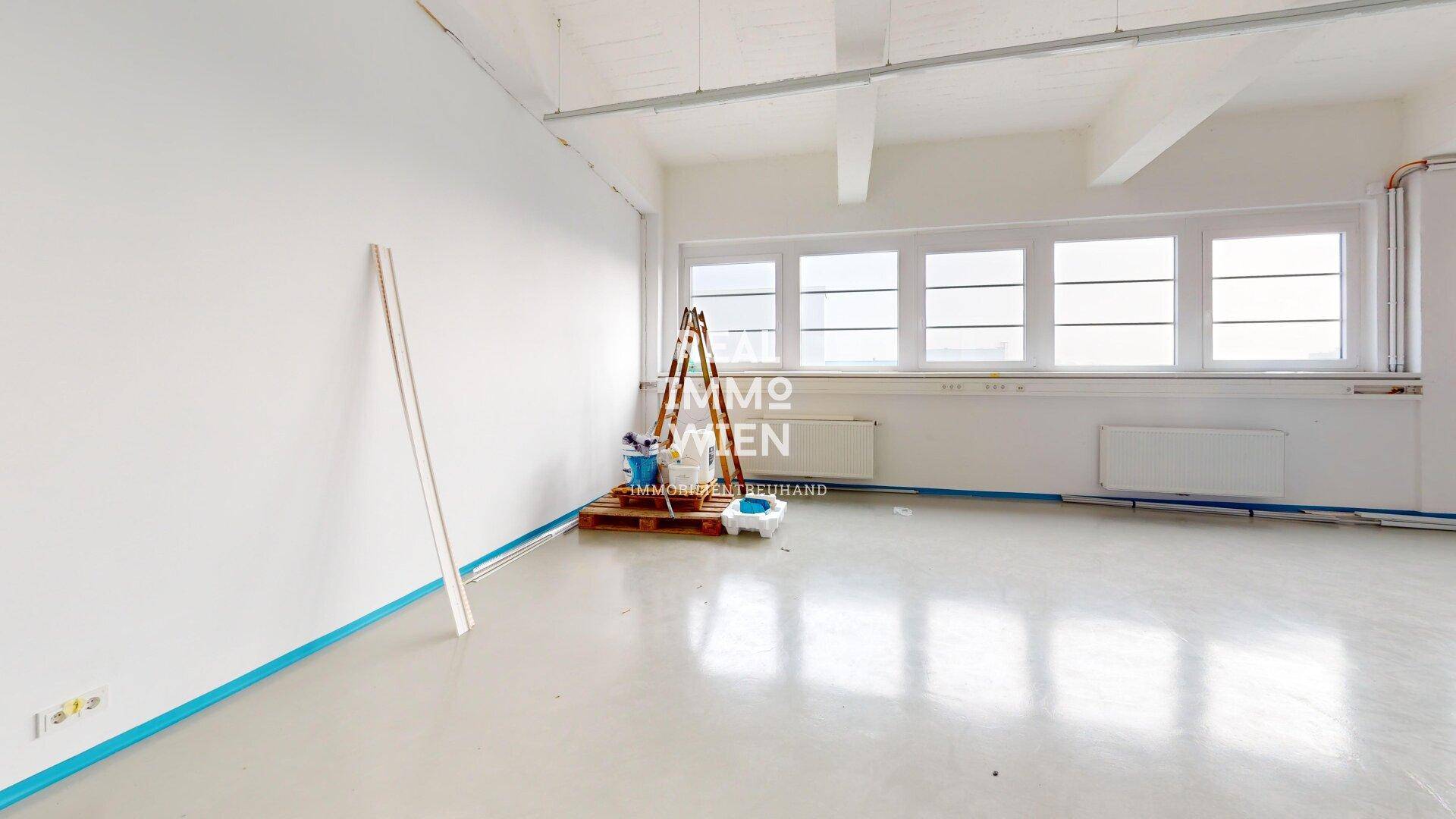 Heller Büroraum mit großen Fenstern, hohen Decken und glänzendem Boden, ideal für flexible Arbeitsplatzgestaltung.