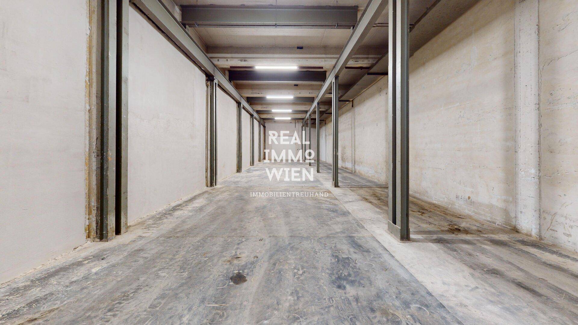 Perspektive eines langen Industrieraums mit Betonboden, hohen Decken und einer Reihe von Metallträgern.