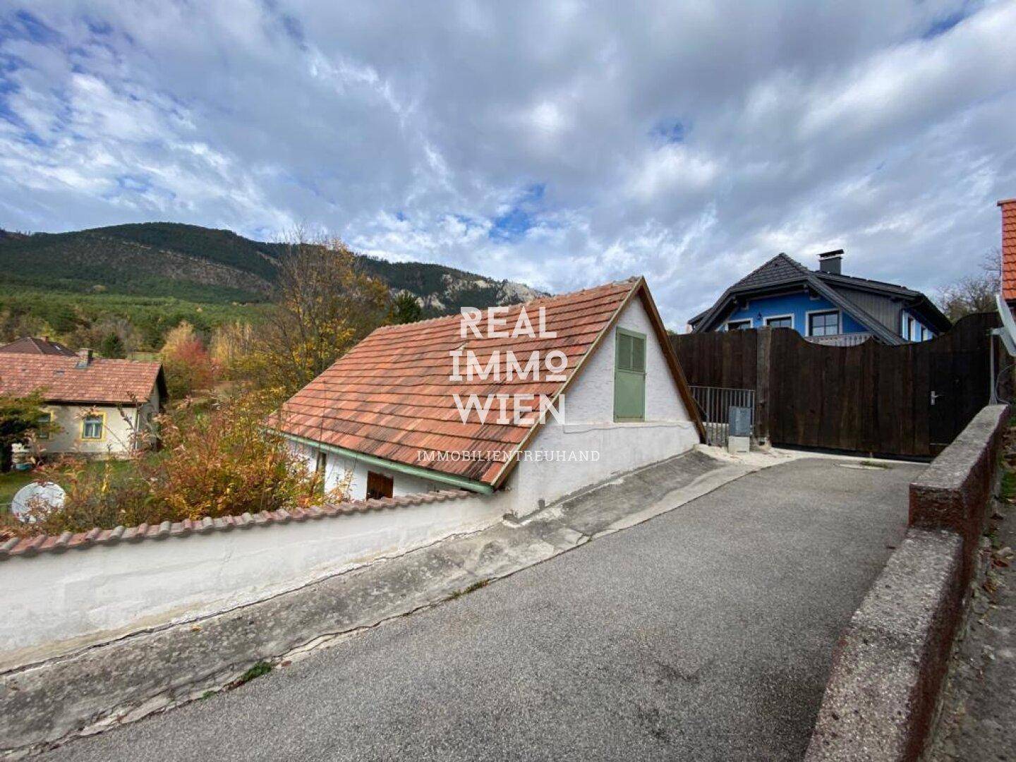 Zufahrt zum Haus mit schrägem Dach und Blick auf die umliegende Hügellandschaft.
