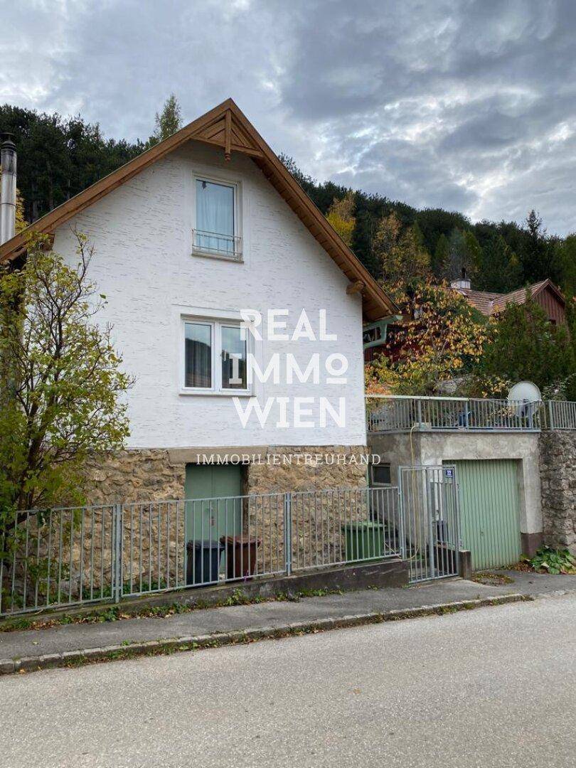 Ansicht des Hauses von der Straße mit Steinfassade im Erdgeschoss und integrierter Garage.