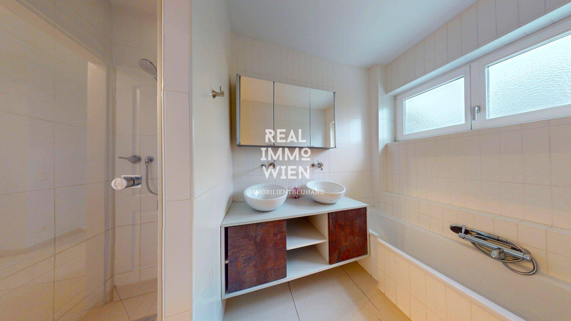 Badezimmer mit Doppelwaschbecken, Badewanne, Dusche und Fenster für Tageslicht.