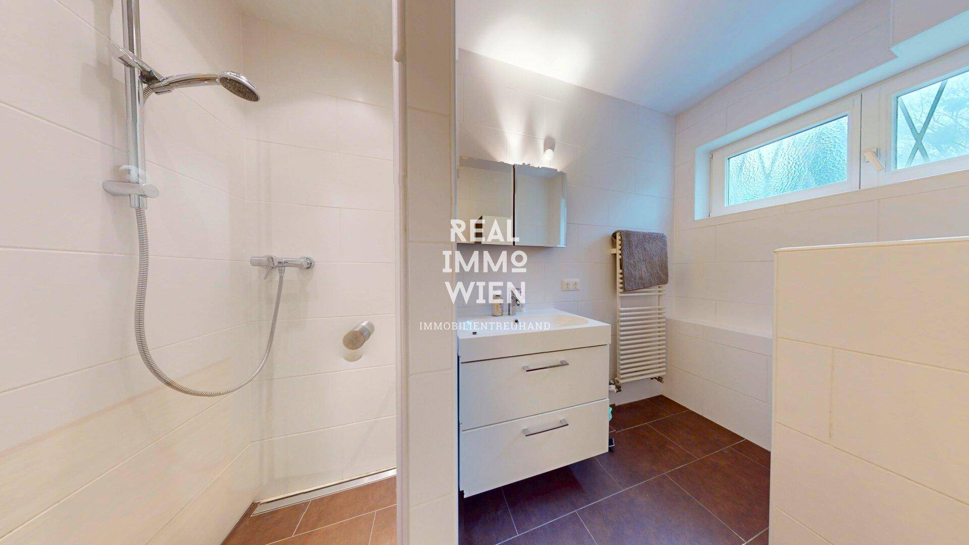 Modernes Badezimmer mit Dusche, Einzelwaschbecken und beheiztem Handtuchhalter.