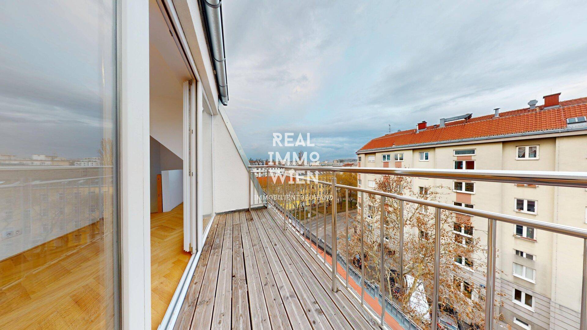 Geräumiger Balkon mit Holzboden und Metallgeländer, bietet einen weiten Blick auf die umliegenden Gebäude und die Stadt.