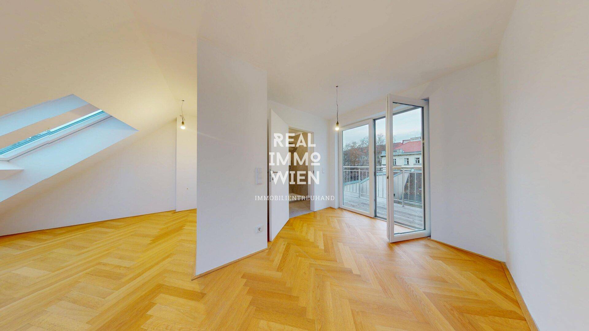 Geräumiger Wohnbereich mit Fischgrätparkett und großen Fenstertüren, die viel Licht hereinlassen und den Raum öffnen.