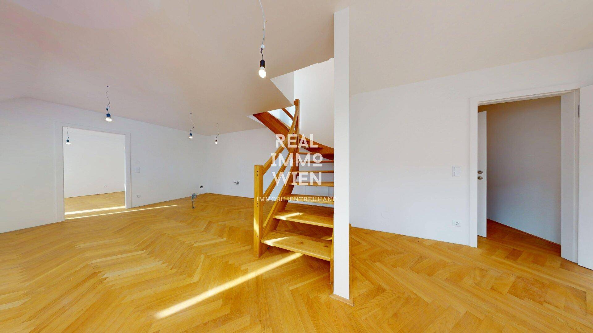 Geräumiger Wohnbereich mit Holzparkett und einer eleganten Holztreppe, die in die obere Etage führt und den Raum strukturiert.