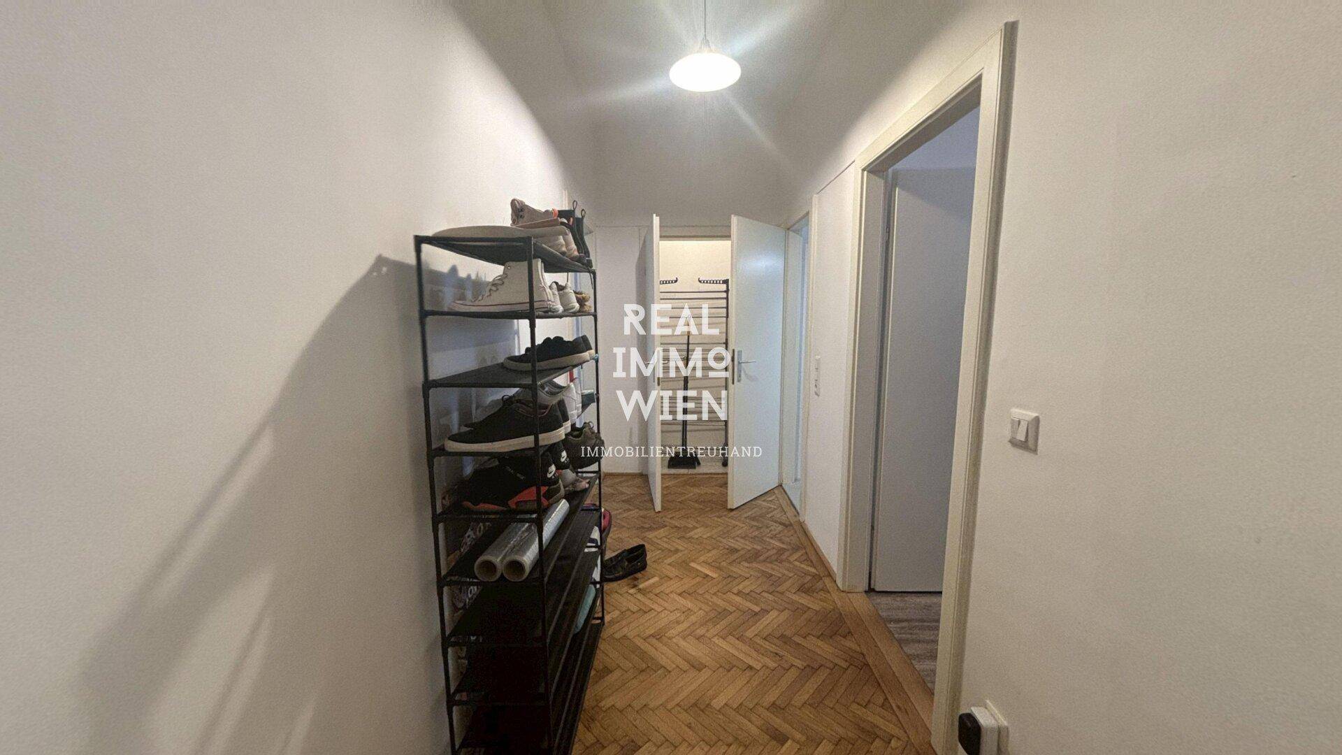 Langer Flur mit Fischgrätparkett und praktischem Schuhregal.