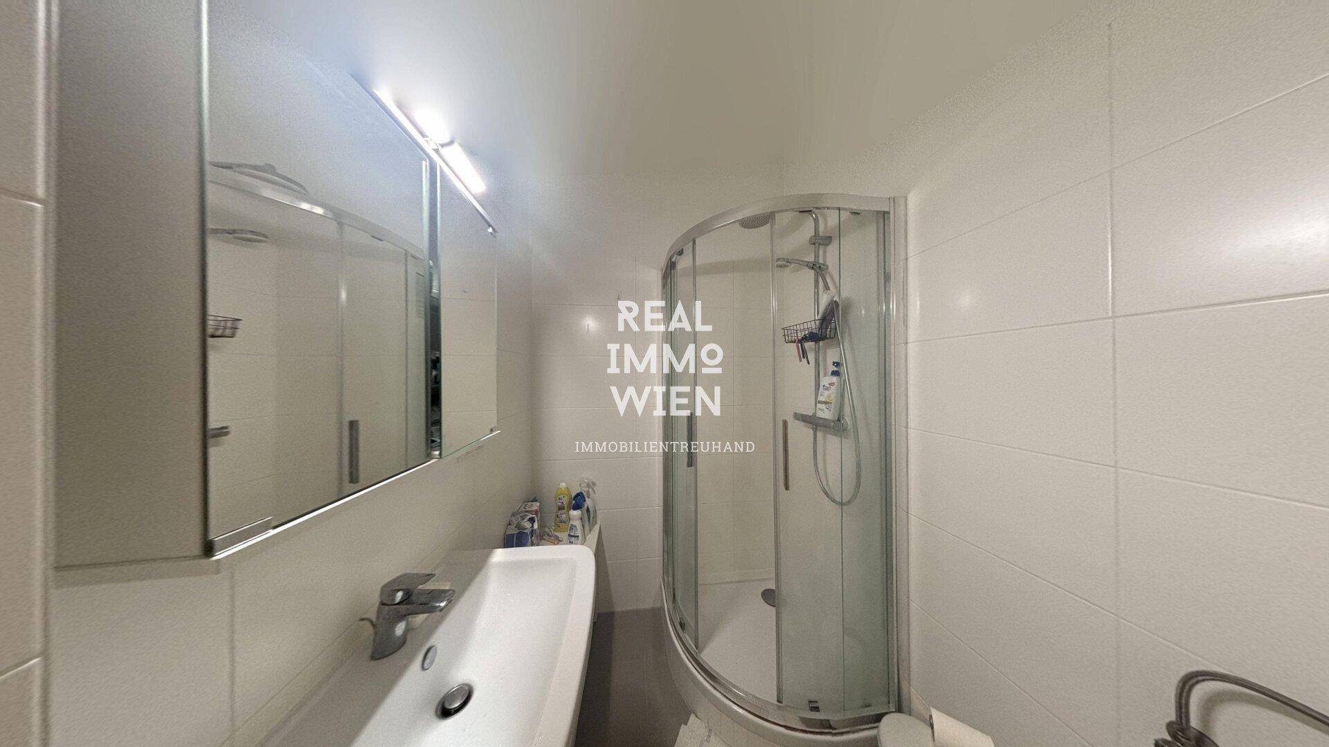 Modernes Badezimmer mit Duschkabine, Waschbecken und Spiegelschrank.