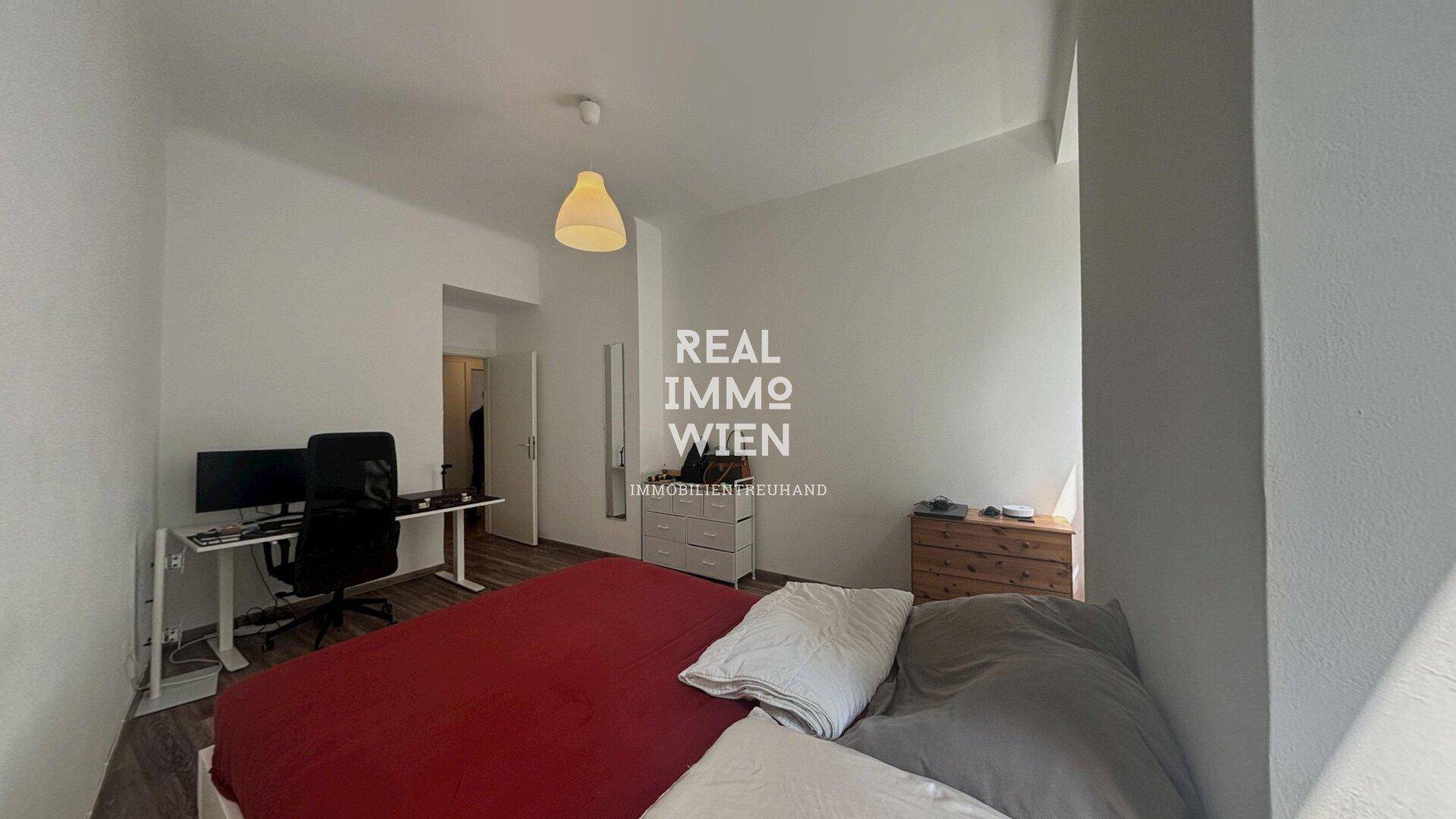 Geräumiges Schlafzimmer mit Bett, Schreibtisch und viel Tageslicht durch die Fenster.