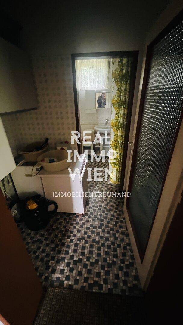 Badezimmer mit gemusterten Fliesen, Waschbecken und einem Fenster für natürliche Belüftung.