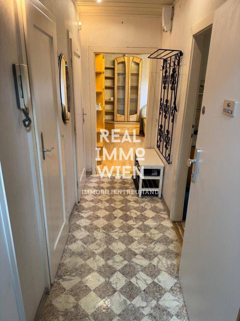 Flur mit gemusterten Fliesen, Garderobe und Blick in angrenzende Räume.