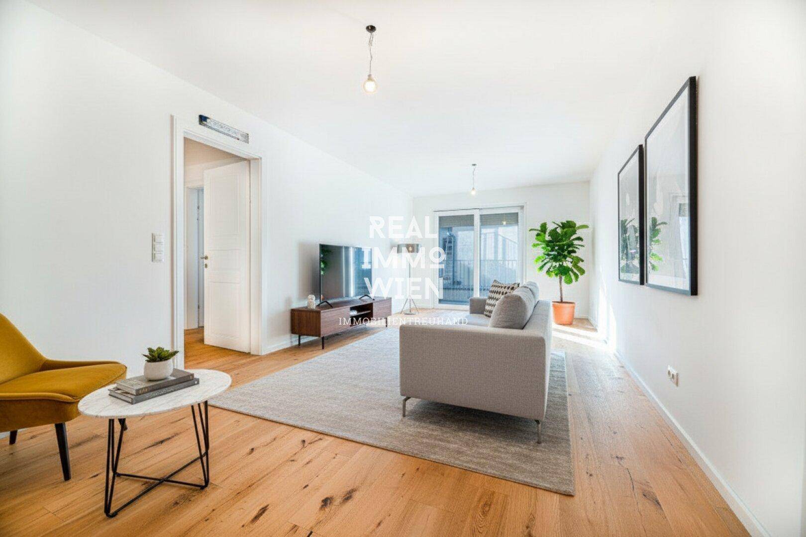 Modern eingerichtetes Wohnzimmer mit Sofa, Holzboden und Zugang zu einem Balkon.