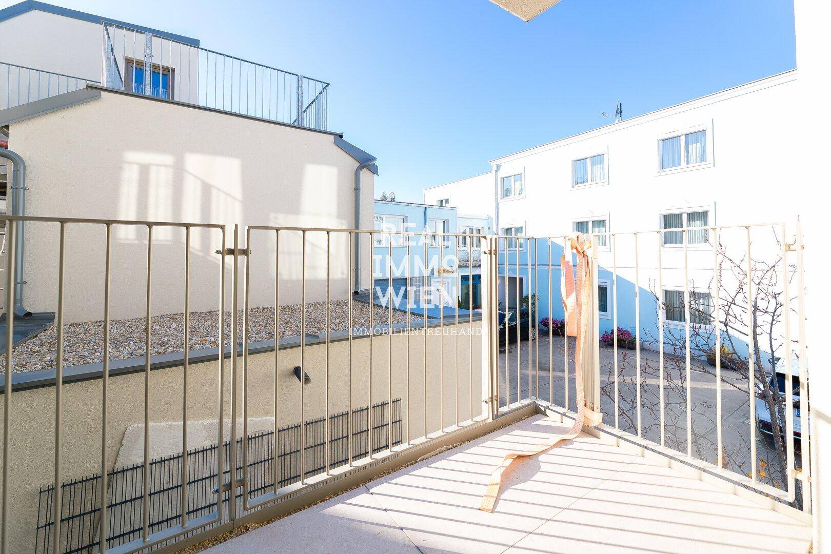 Sonniger Balkon mit Metallgeländer und Blick auf die umliegenden Gebäude.