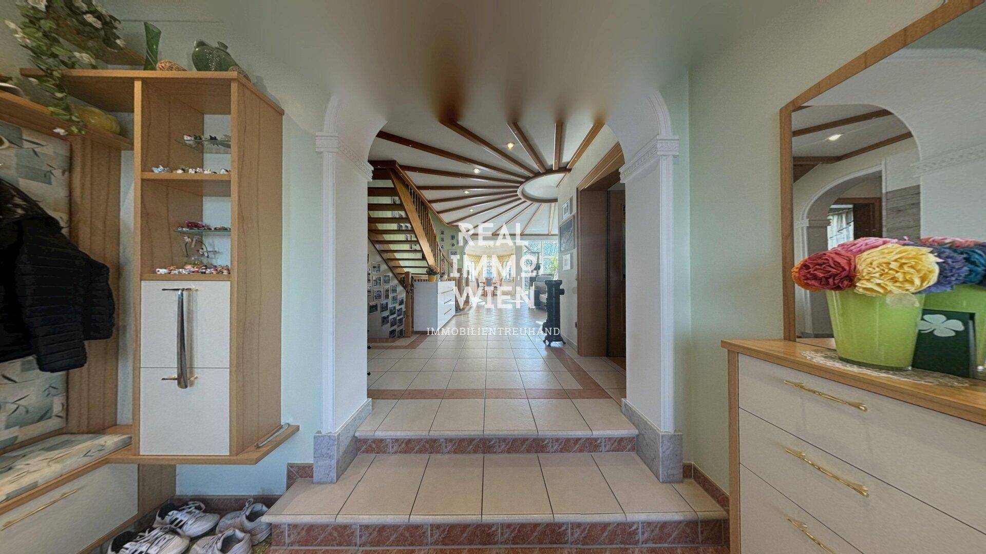 Heller Eingangsbereich mit gefliestem Boden, Garderobe und Treppe zum Obergeschoss.