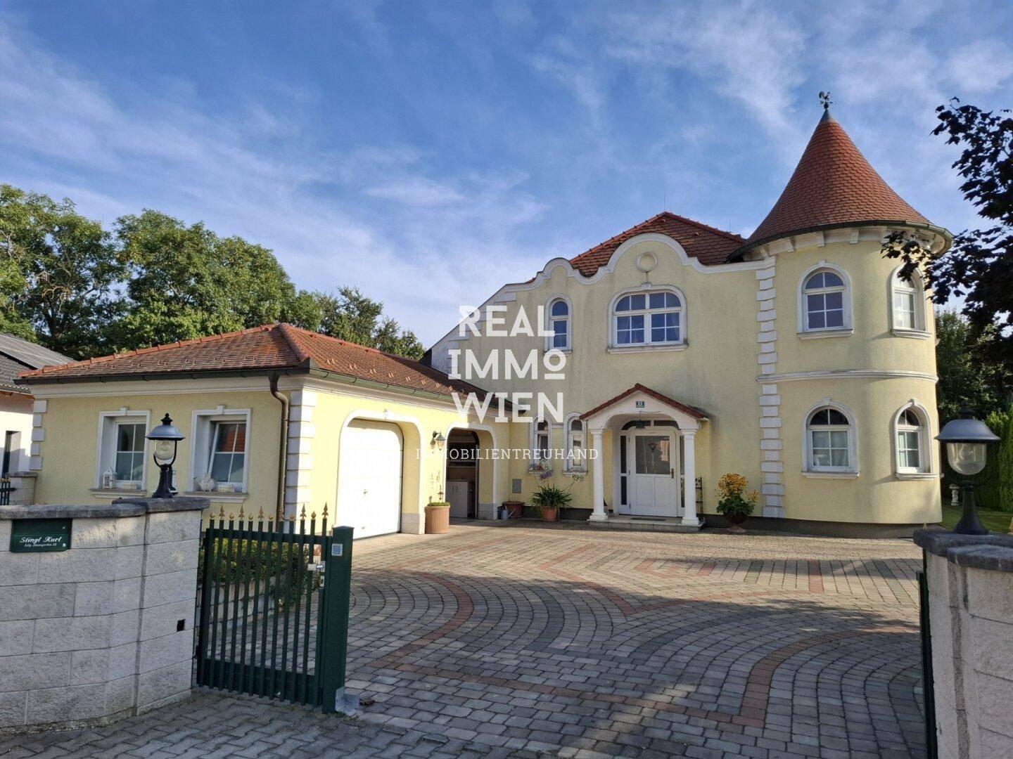 Elegante Villa mit gepflasterter Auffahrt, integrierter Garage und klassischer Architektur.